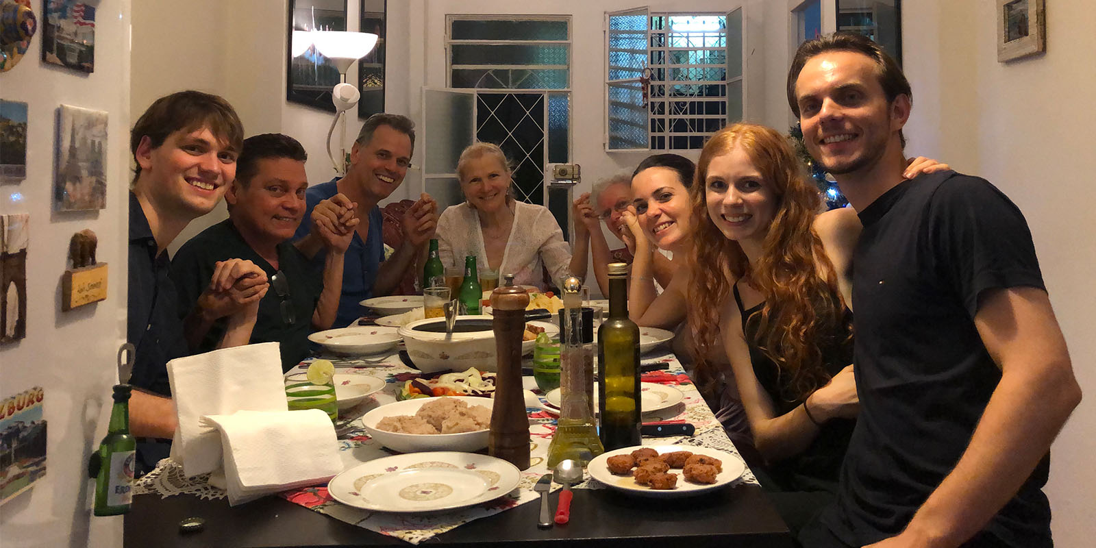 Two happy families sit around a table covered with plates of food