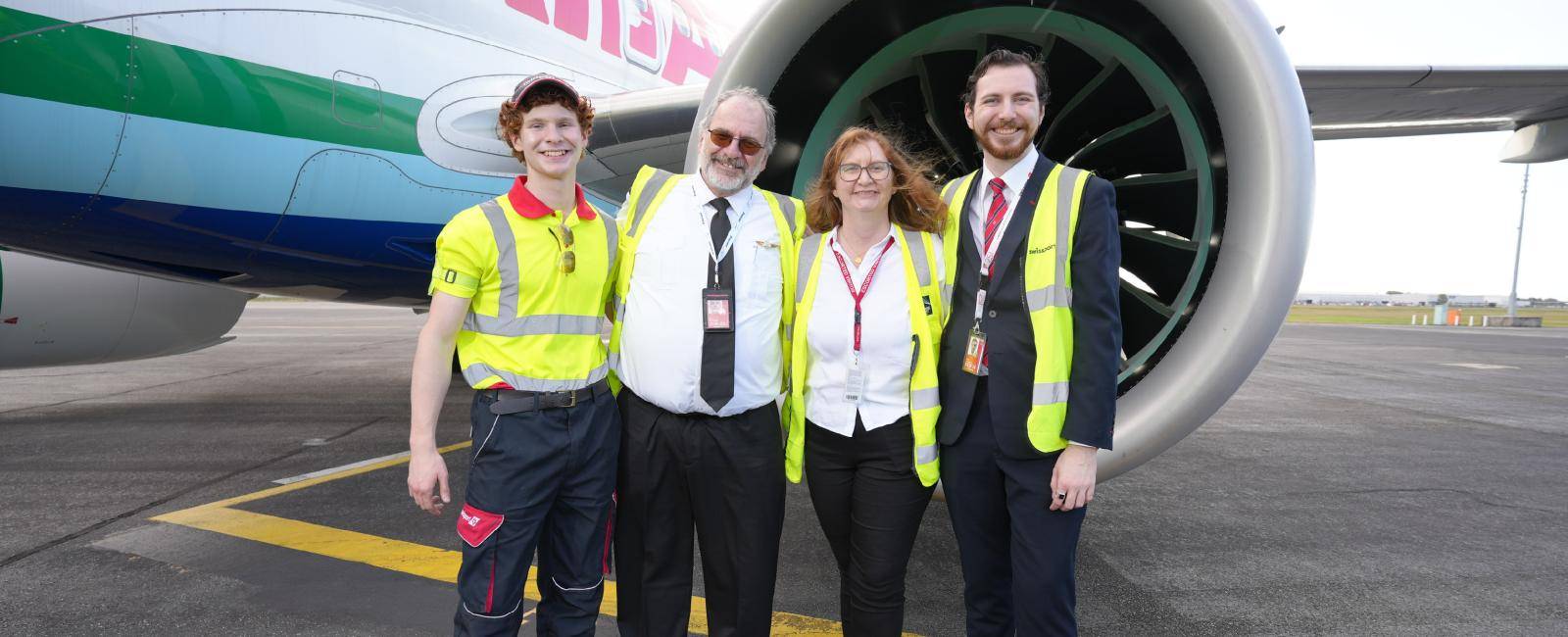 Family of four in yellow high-vis in front of a jet engine